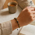 UNIQAL Perlenarmband am Handgelenk – getragen beim Lesen & Kaffee, dezent & stilvoll